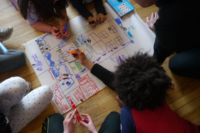 Kids drawing on a large piece of paper.