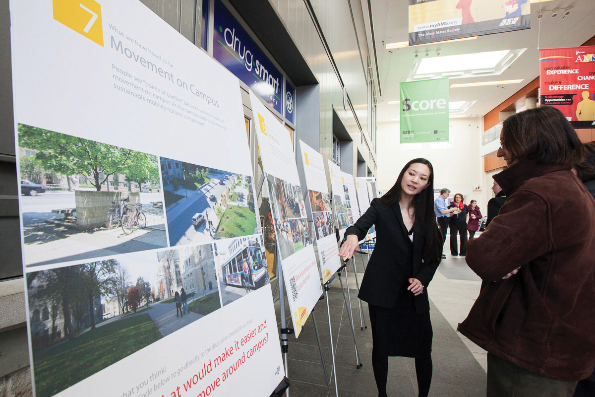 Students reading posters at university campus engagement session.